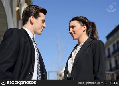 Attractive business people talking outside of company building. Couple working.