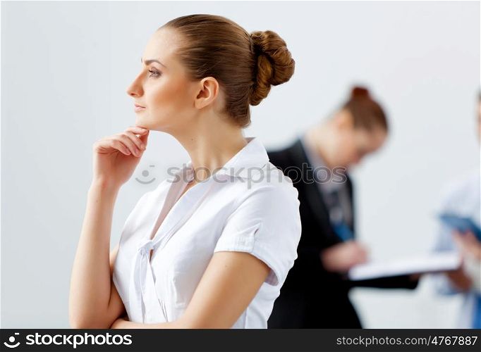 Attractive business woman thinking. Attractive businesswoman looking thoughtfully with colleagues at background