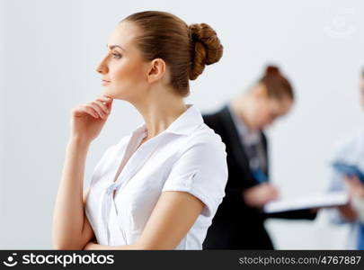 Attractive business woman thinking. Attractive businesswoman looking thoughtfully with colleagues at background