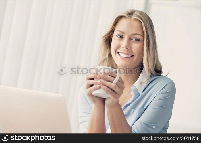Attractive business woman with a mug in office