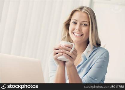 Attractive business woman with a mug in office
