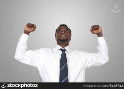 Attractive businessman celebrating a triumph a over grey background