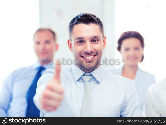 attractive businessman in office showign thumbs up. businessman in office showign thumbs up