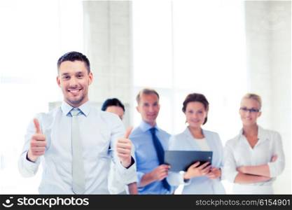 attractive businessman in office showign thumbs up. businessman in office showign thumbs up