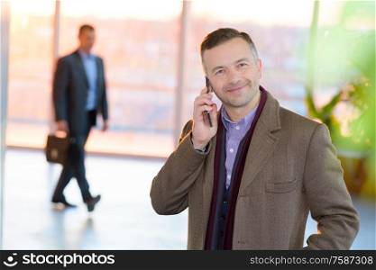attractive businessman in suit standing and talking on phone