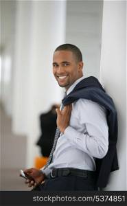Attractive businessman leaning against wall with his jacket over his shoulder
