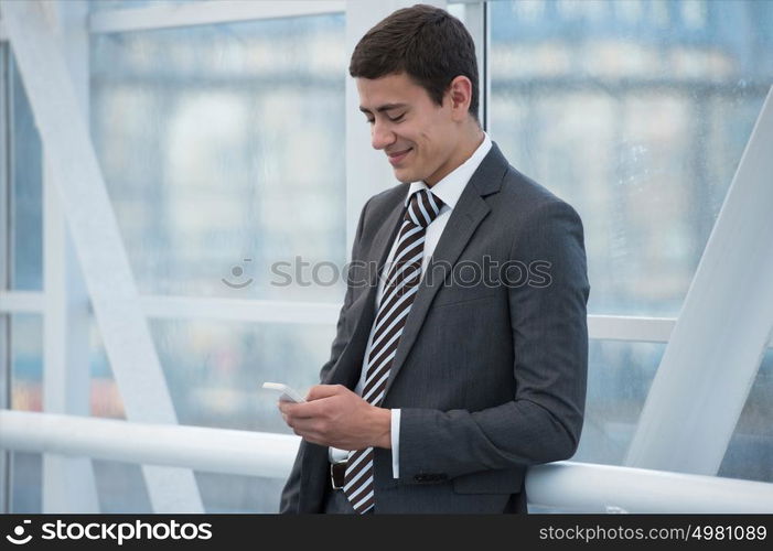 Attractive businessman using his smartphone in office building