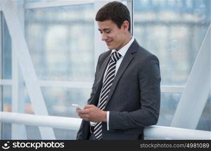 Attractive businessman using his smartphone in office building