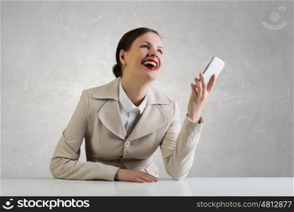 Attractive businesswoman having mobile conversation. Young pretty businesswoman sitting at table with mobile phone in hand