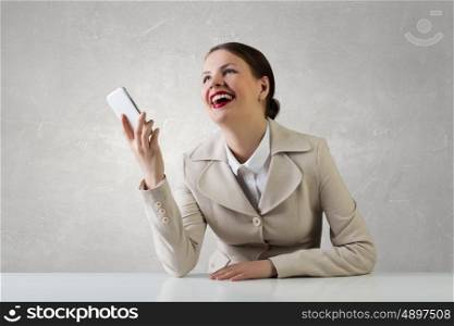 Attractive businesswoman having mobile conversation. Young pretty businesswoman sitting at table with mobile phone in hand