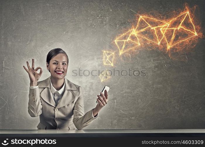 Attractive businesswoman in grunge style. Beautiful businesswoman with phone in hand sitting at table and showing ok gesture