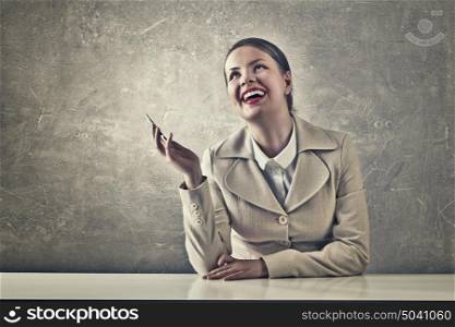 Attractive businesswoman in grunge style. Beautiful businesswoman with phone in hand sitting at table and laughs