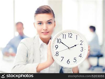 attractive businesswoman showing white clock in office. businesswoman showing white clock in office