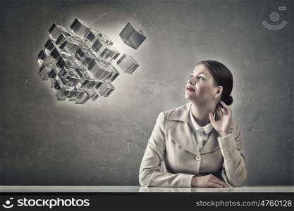 Attractive businesswoman sitting at table. Young businesswoman sitting at table and looking away on cube figure