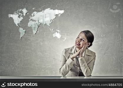Attractive businesswoman sitting at table. Young businesswoman sitting at table and looking dreamily at world map