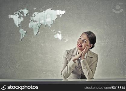 Attractive businesswoman sitting at table. Young businesswoman sitting at table and looking dreamily at world map