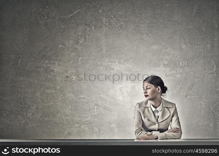 Attractive businesswoman sitting at table. Young businesswoman sitting at table and looking away