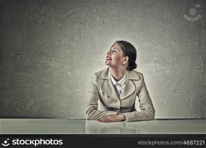 Attractive businesswoman sitting at table. Young businesswoman sitting at table and looking away