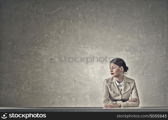 Attractive businesswoman sitting at table. Young businesswoman sitting at table and looking away