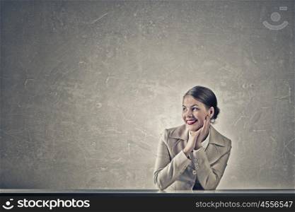 Attractive businesswoman sitting at table. Young businesswoman sitting at table and looking dreamily away