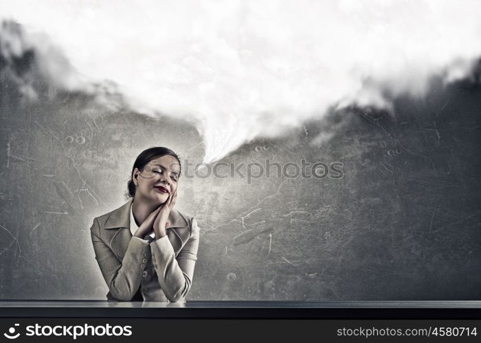 Attractive businesswoman sitting at table. Young businesswoman sitting at table and looking dreamily away