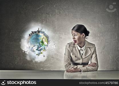 Attractive businesswoman sitting at table. Young businesswoman sitting at table and looking with shock away. Elements of this image are furnished by NASA