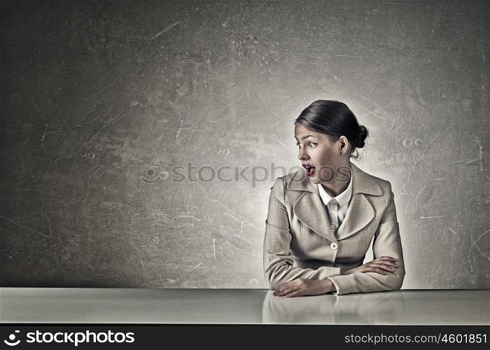 Attractive businesswoman sitting at table. Young businesswoman sitting at table and looking with shock away