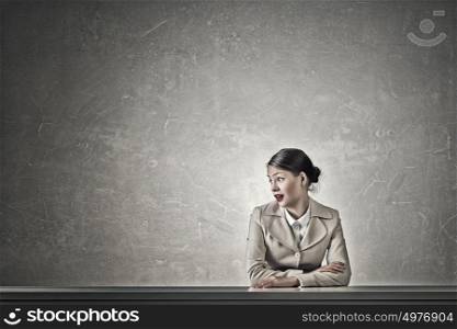 Attractive businesswoman sitting at table. Young businesswoman sitting at table and looking with shock away