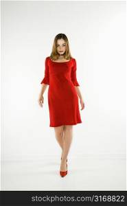 Attractive Caucasian woman wearing red dress walking to viewer.
