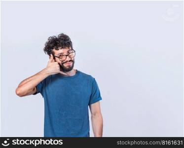 Attractive caucasian young male in casual clothes imitates telephone conversation, keeps hand near ear as if holding mobile phone