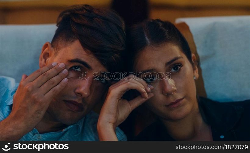 Attractive cheerful young caucasian couple crying while watching film in movie theater. Lifestyle entertainment concept. Close up shot.