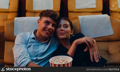 Attractive cheerful young caucasian couple laughing while watching film in movie theater. Lifestyle entertainment concept.