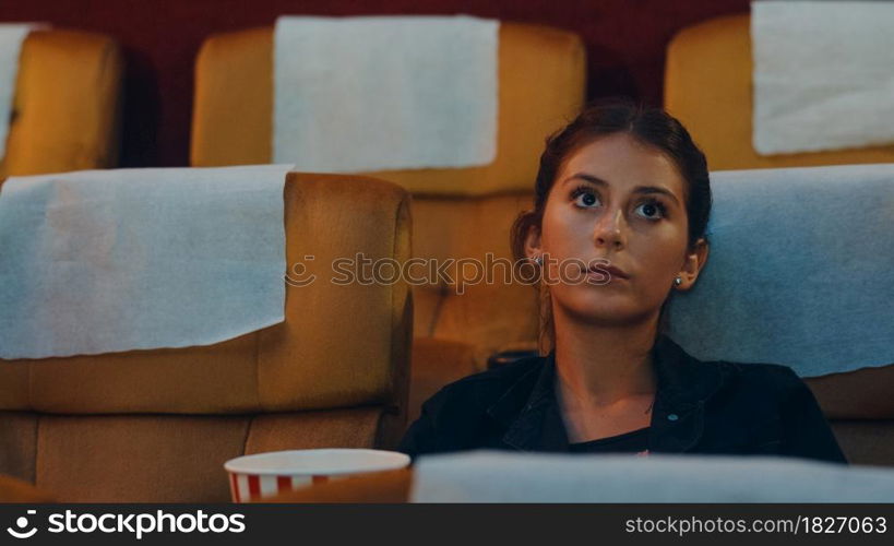 Attractive cheerful young caucasian lady laughing while watching film in movie theater. Lifestyle entertainment concept. Close up shot.