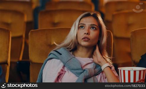 Attractive cheerful young caucasian woman watching horror movie in cinema theater. Lifestyle entertainment concept.