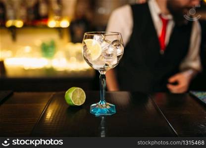 Attractive cocktail and lime on wooden counter. Advertising of alcoholic beverages