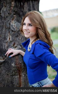 Attractive cool woman dressed in blue against a tree