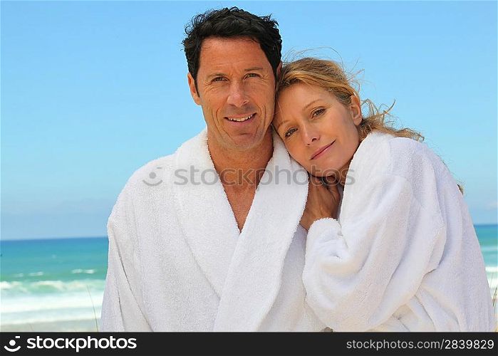 Attractive couple in bathrobes on the beach