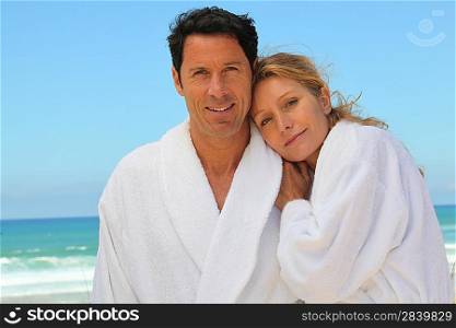 Attractive couple in bathrobes on the beach