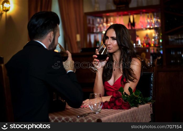 Attractive couple in love is dating and drinking wine during romantic dinner in the restaurant.