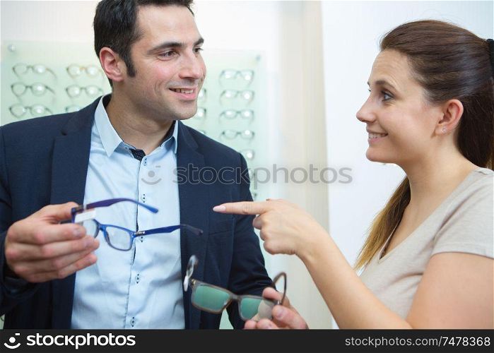attractive couple in optical store buying glasses and smiling