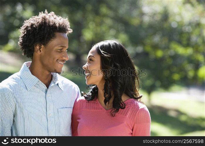 Attractive couple in park looking at eachother smiling.