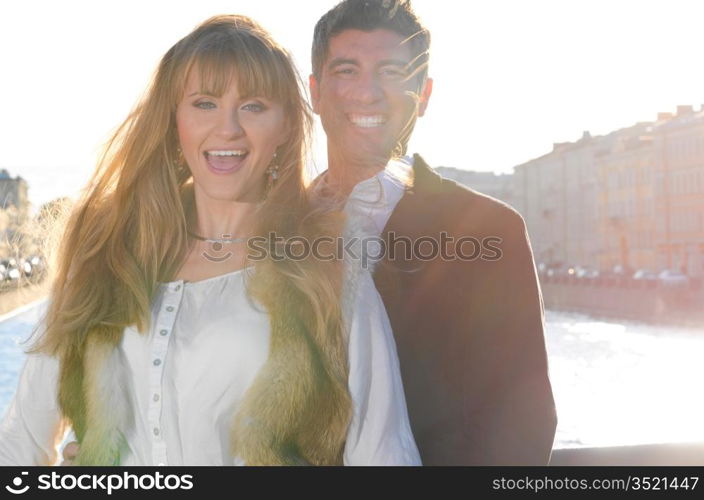 attractive couple is sincerely laughing on street in sunlight flare
