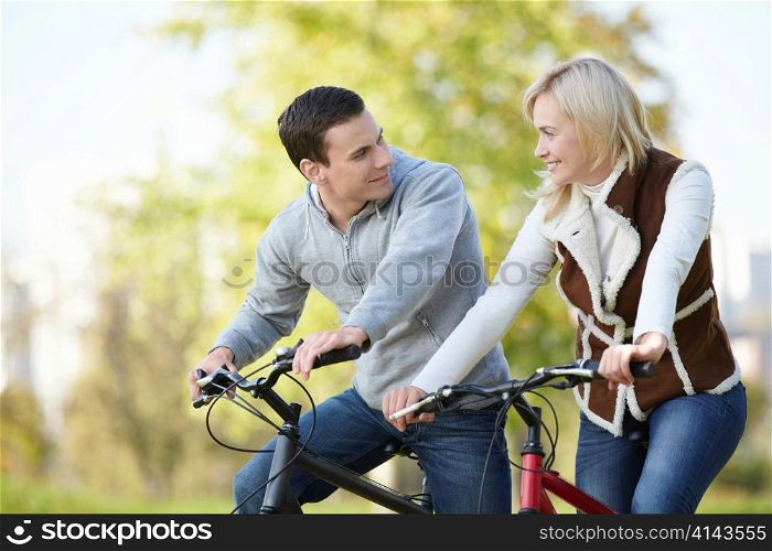 Attractive couple on bicycles looking at each other