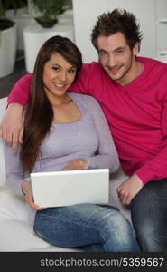 Attractive couple sat with laptop computer