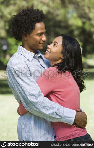 Attractive couple smiling and embracing in park.