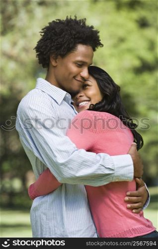 Attractive couple smiling and embracing in park.