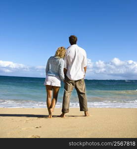Attractive couple standing leaning on eachother looking out at ocean in Maui, Hawaii.