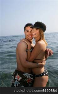 Attractive couple stood in the sea hugging