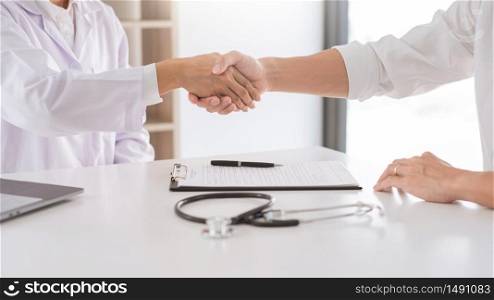 Attractive Doctor and patient shaking hands for encouragement and empathy, healthcare and assistance, Medical concept