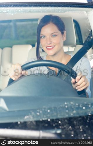 Attractive elegant businesswoman driving luxury new car smiling behind window